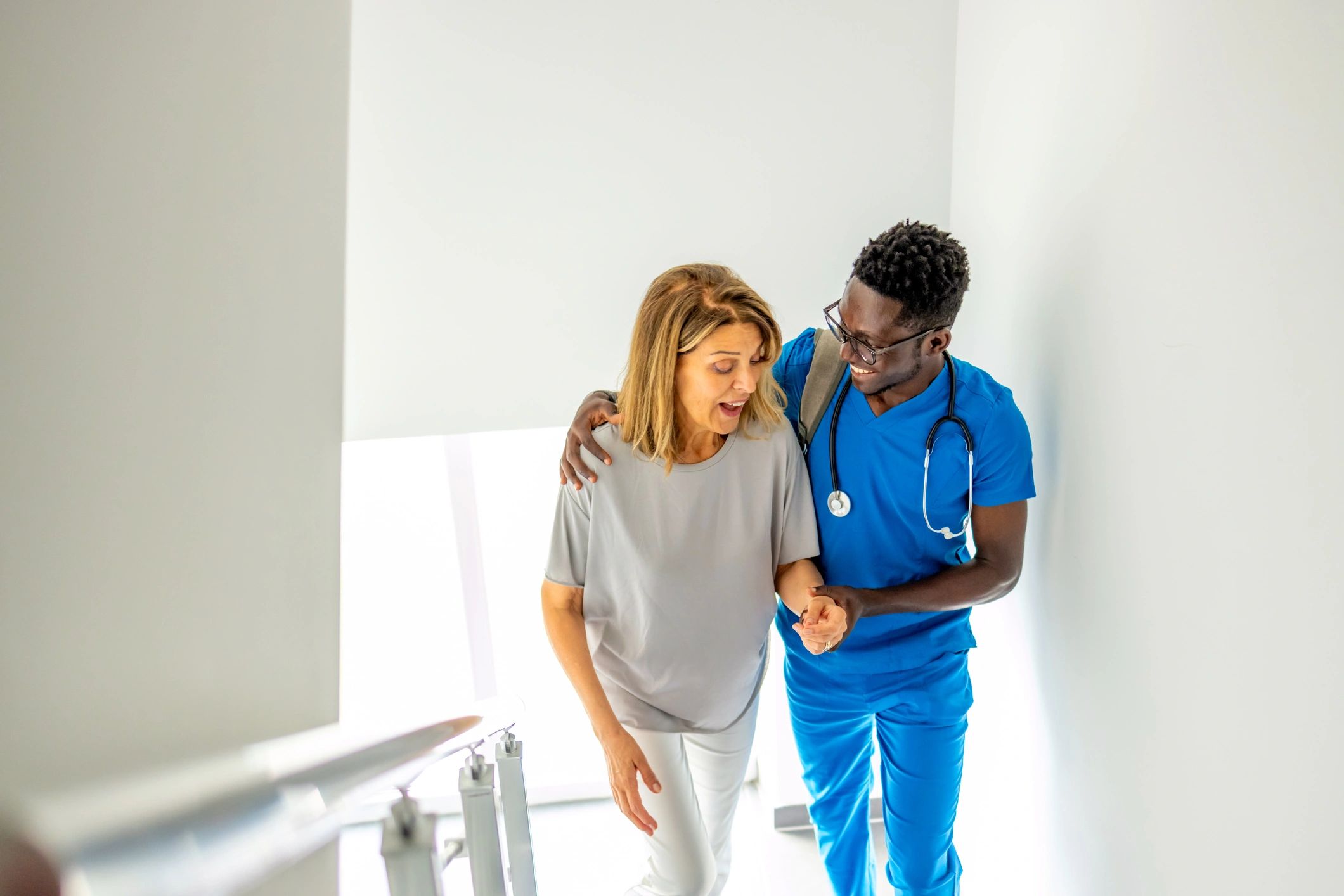 Nurse assisting a senior woman walking up stairs